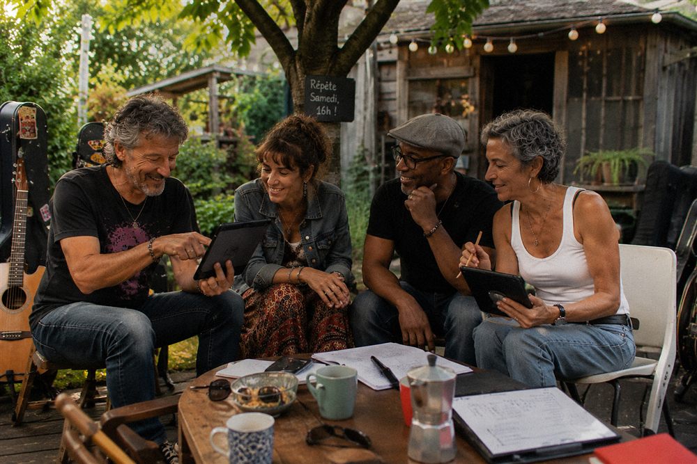 A group of friends preparing for the next rehearsal, tablets and setlist notes on the table